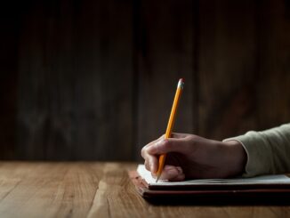 Closeup of woman's hand writing on paper over wooden table