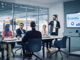 Diverse Modern Office: Businessman Leads Business Meeting with Managers, Talks, uses Presentation TV with Statistics, Infographics. Digital Entrepreneurs Work on e-Commerce Project.